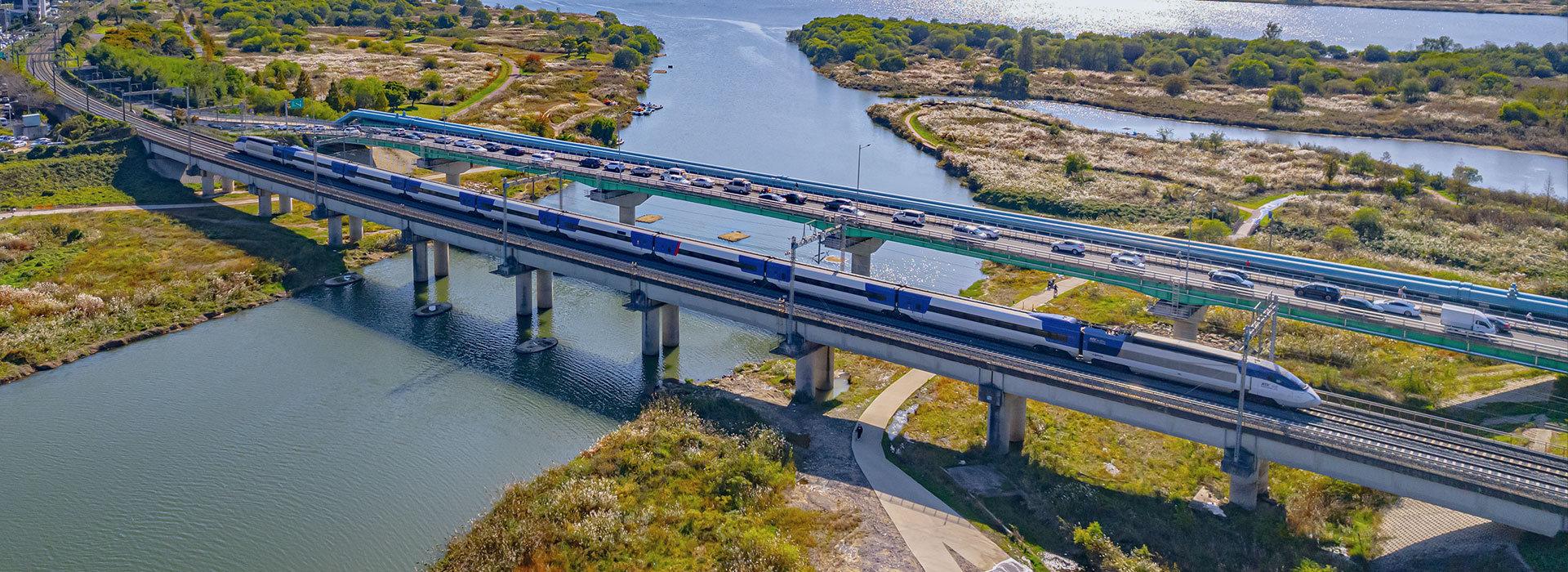 Aerial view of a high-speed train crossing a bridge on a highway