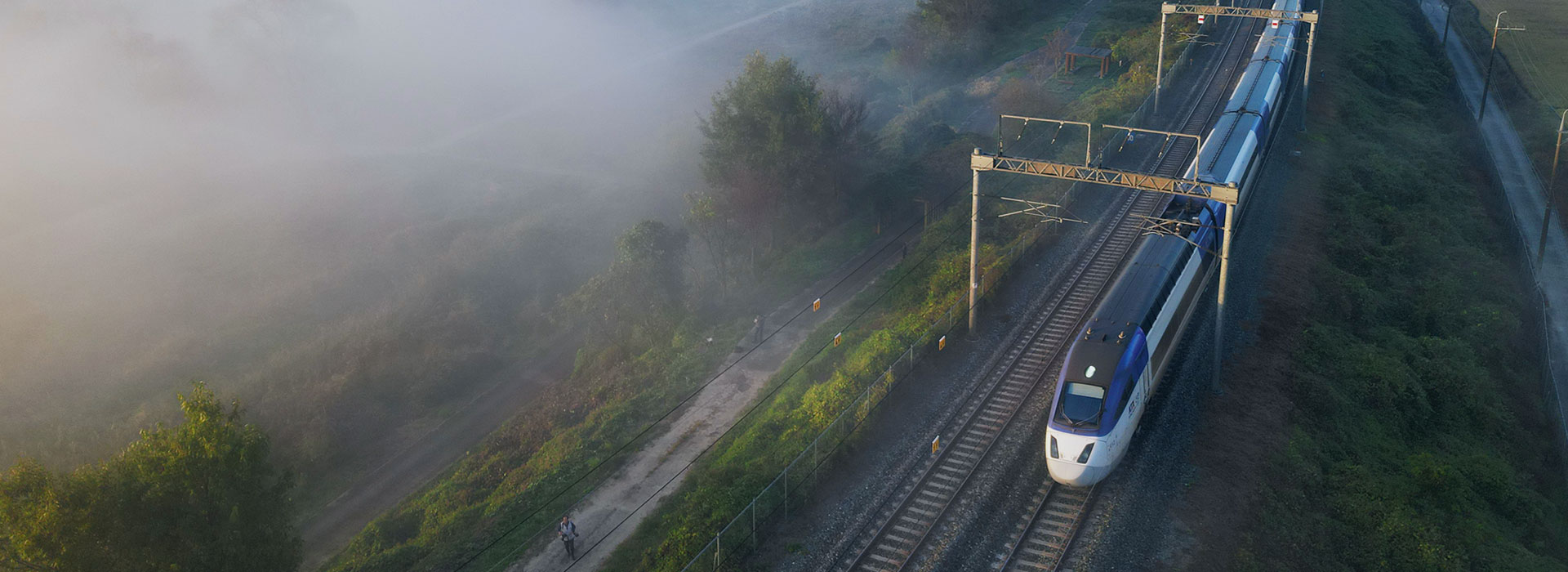 High-speed train passing through foggy farmlands